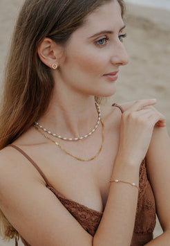 Woman wearing layered necklaces and a bracelet on a blurred background
