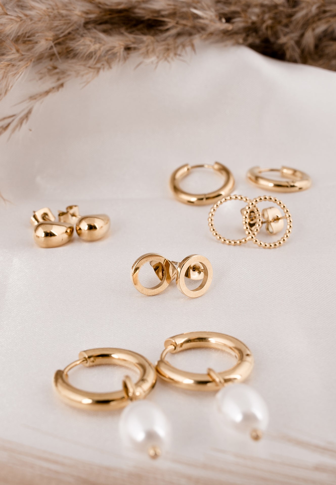 Set of gold earrings on a white surface with a fur background