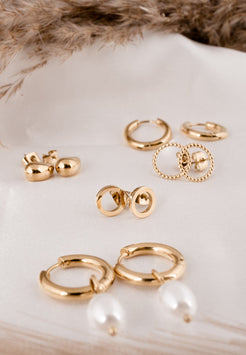 Set of gold earrings on a white surface with a fur background