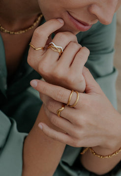 Close-up of hands wearing gold rings with a blurred background