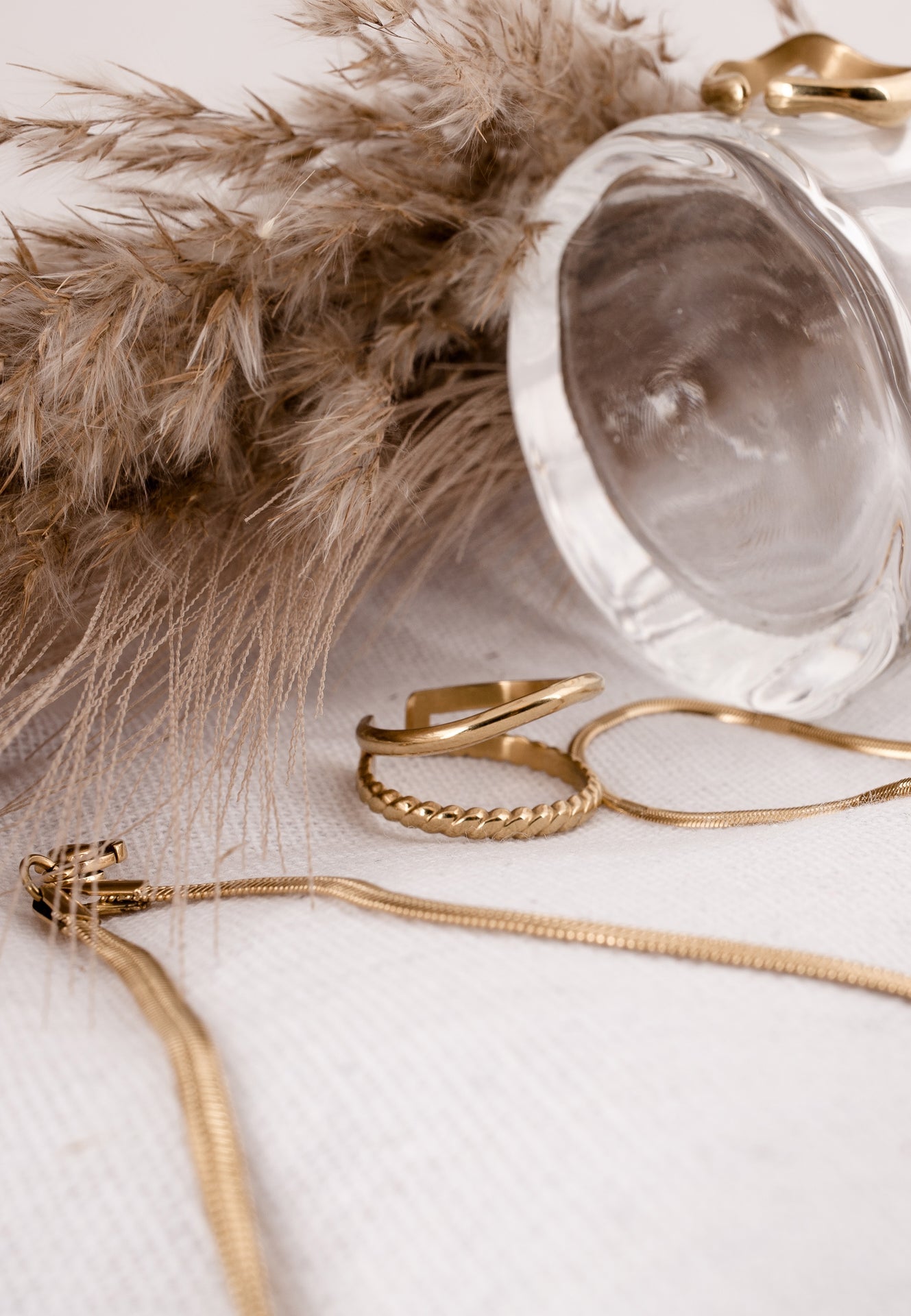 Gold jewelry including a necklace and rings on a light background with decorative elements.
