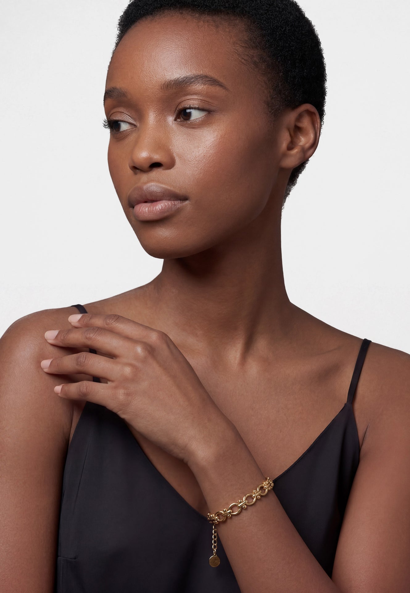 Gold chain bracelet on a wrist with a neutral background