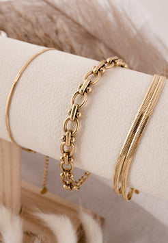 Gold bracelets on a white surface with a soft background