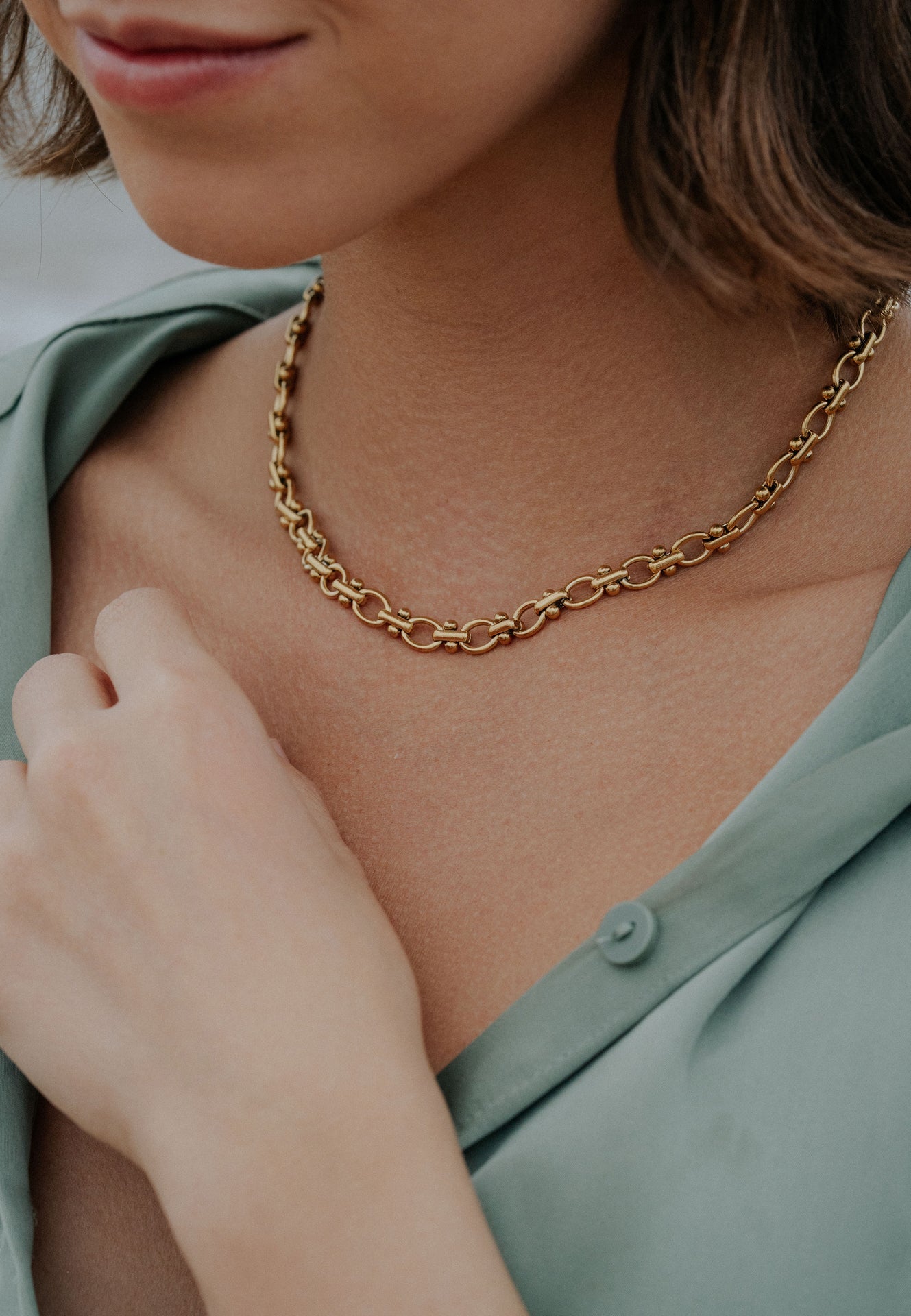 Gold chain necklace worn by a person with a blurred background