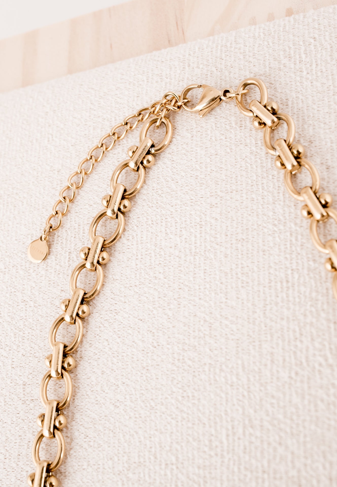 Gold chain necklace on a textured white surface
