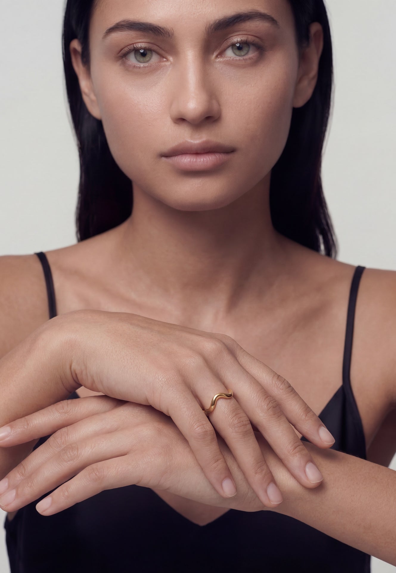 Woman wearing a gold ring with a plain background