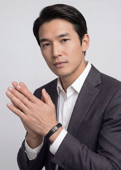 Man in a suit with hands clasped together against a plain background