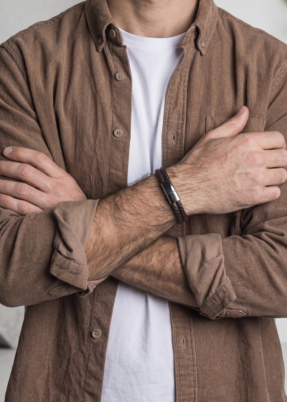 Person wearing a brown shirt over a white shirt with arms crossed.