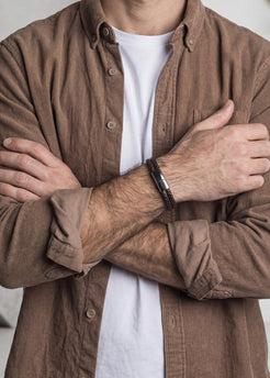 Person wearing a brown shirt over a white shirt with arms crossed.
