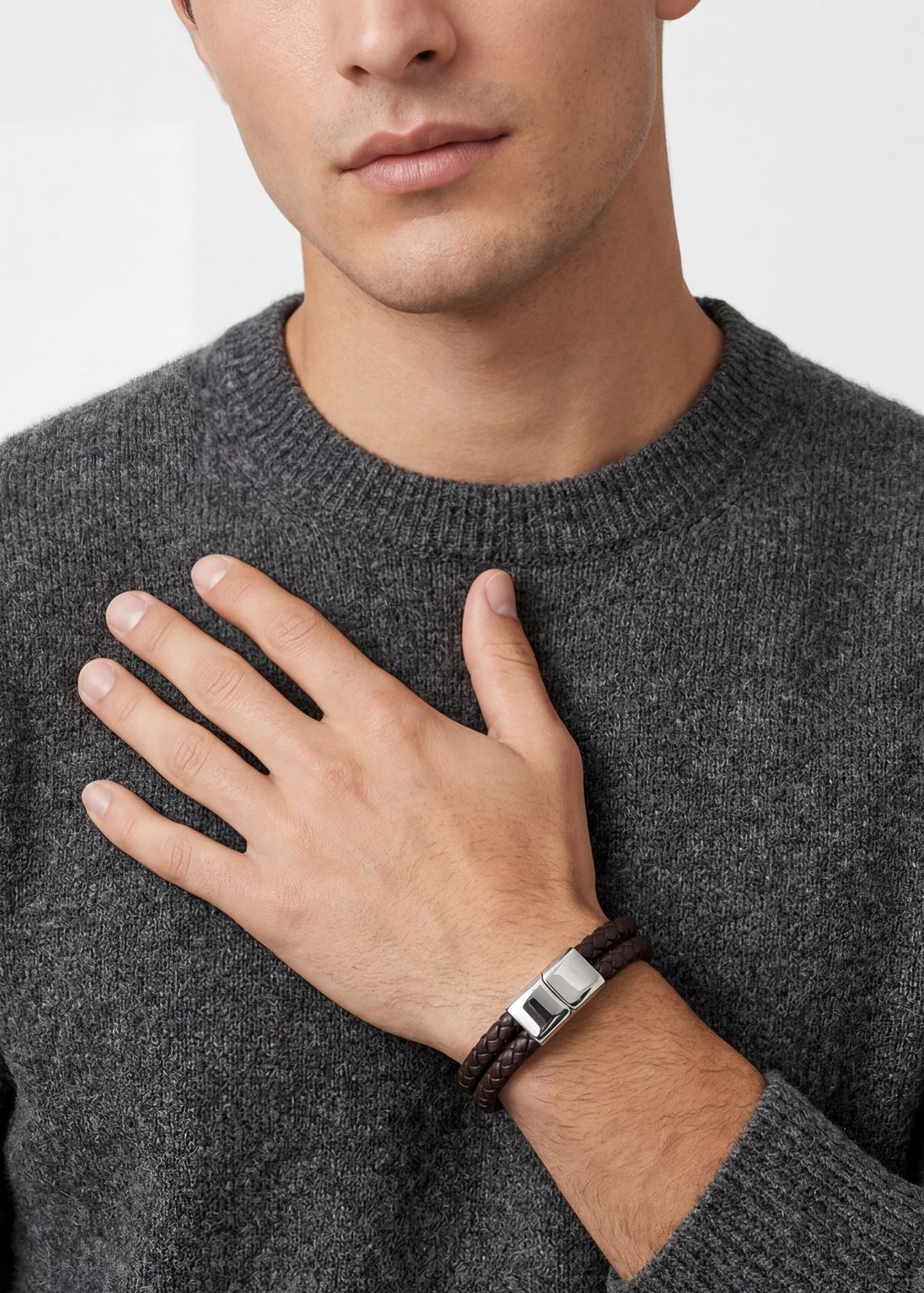 Man wearing a gray sweater and a bracelet on a plain background