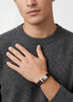 Man wearing a gray sweater and a bracelet on a plain background