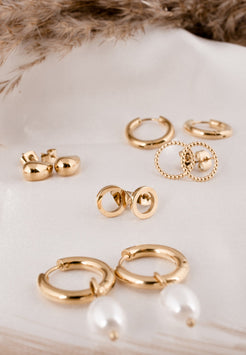 Set of gold earrings on a white shell