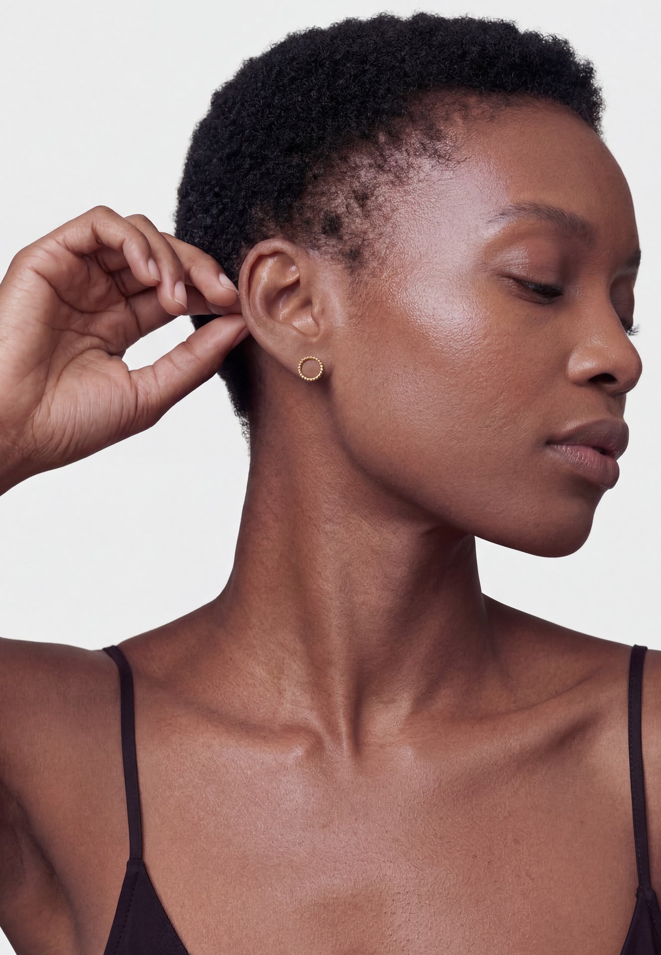Woman wearing a gold earring on a plain background