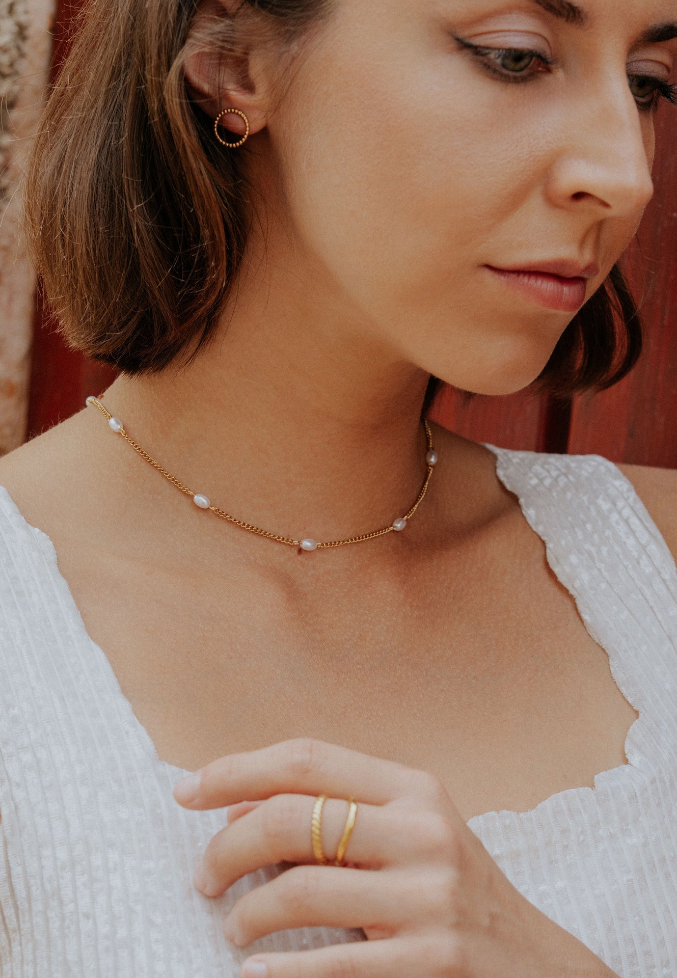 Close-up of a woman wearing a delicate gold necklace with small pearls.