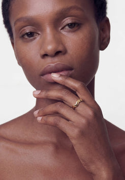 Close-up of a person with a ring on their finger against a plain background