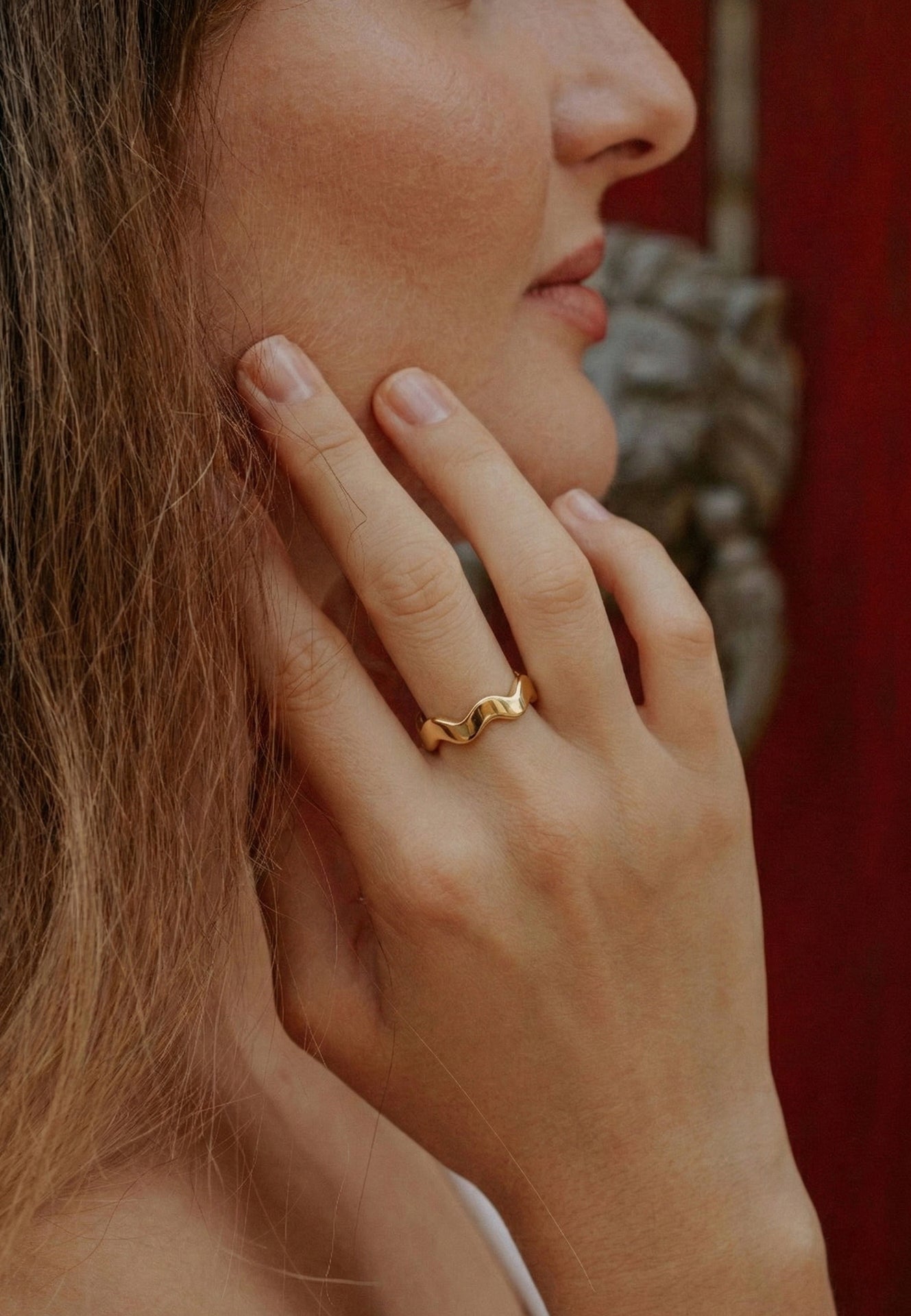 Close-up of a person wearing a gold ring with a decorative background