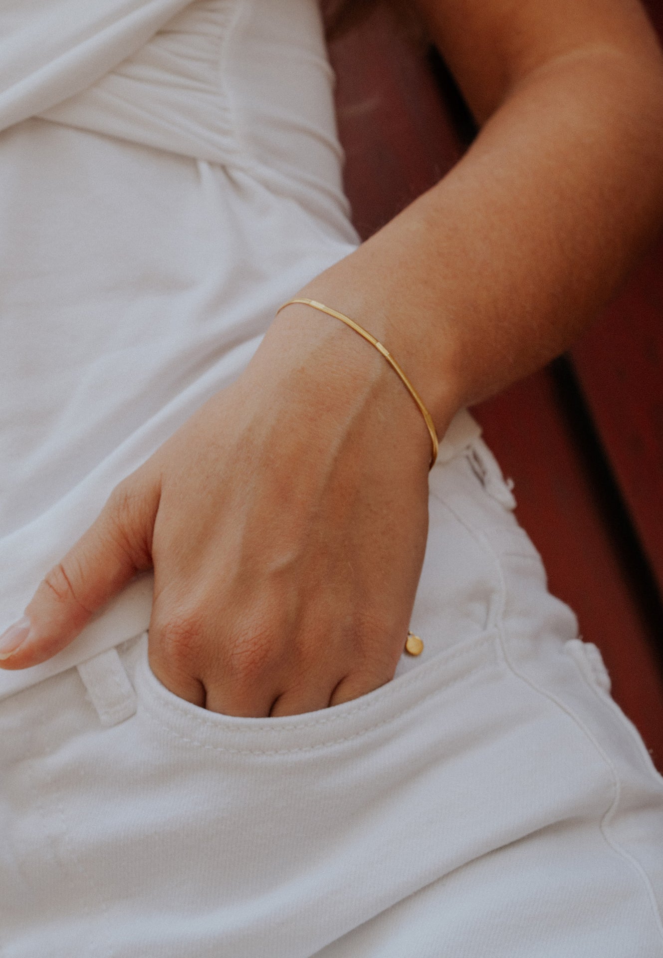Close-up of a hand wearing a gold bracelet with a blurred background