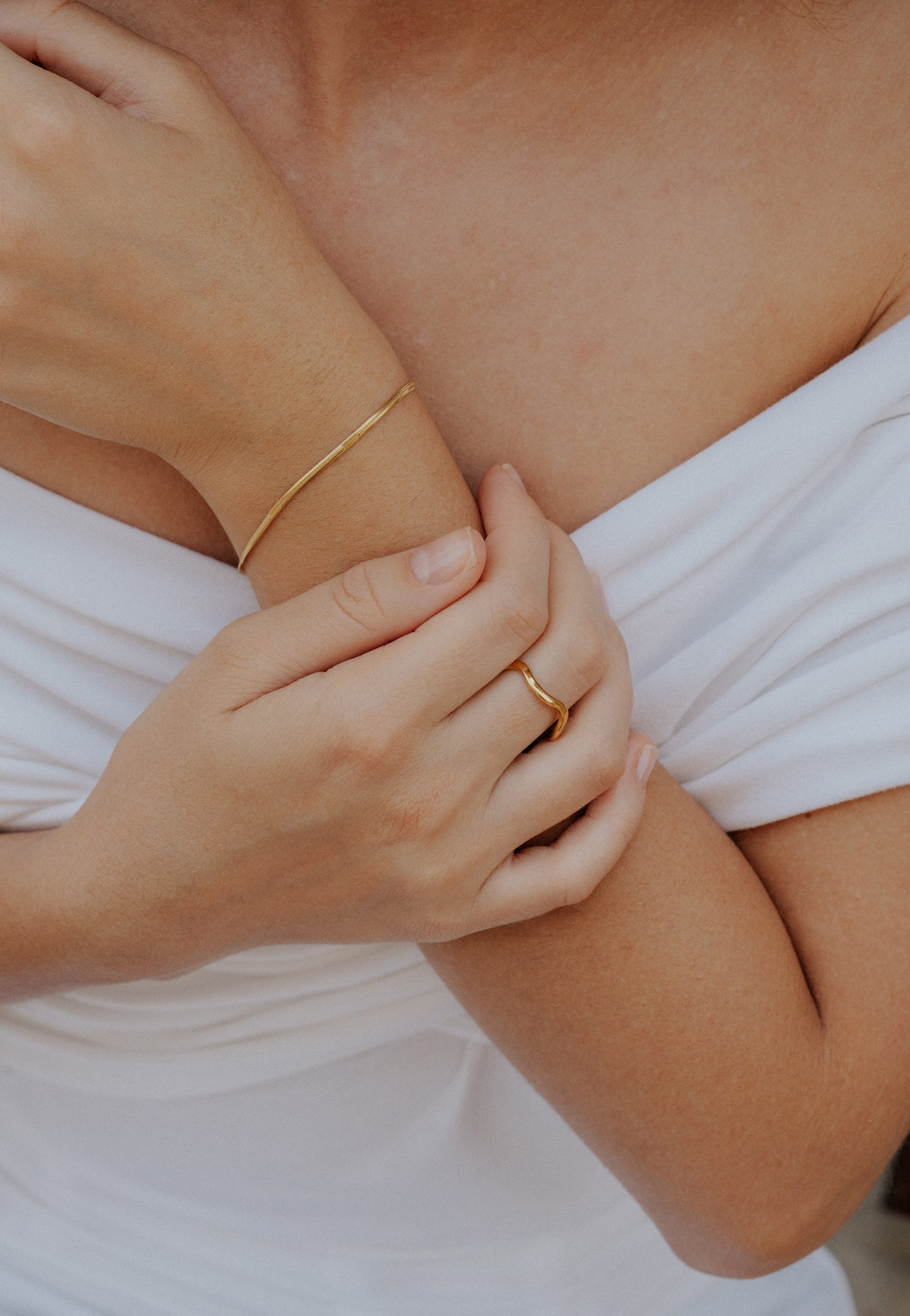 Close-up of a person wearing gold jewelry on a white background