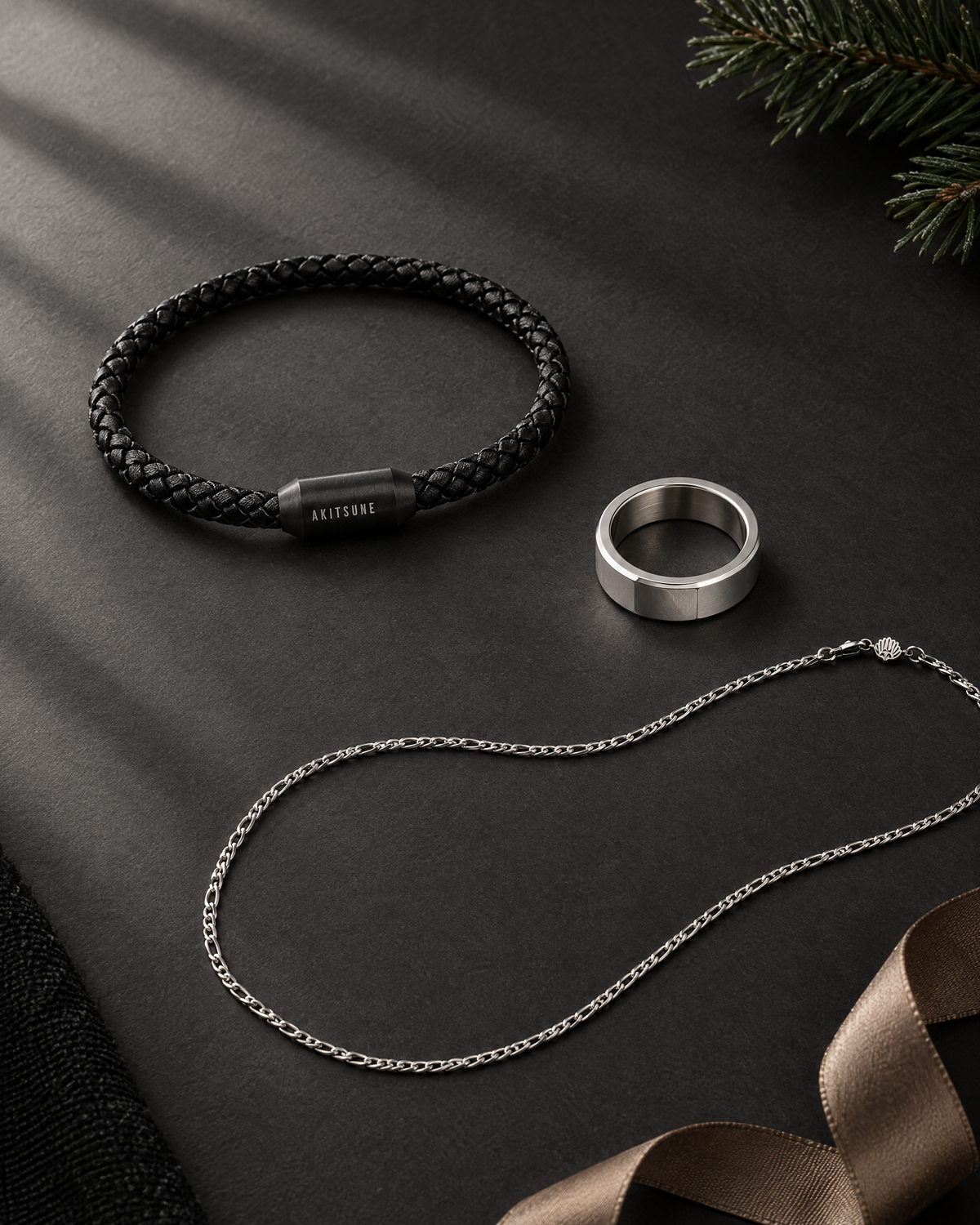 Akitsune Silvus bracelet, Purus ring and Magnas chain on charcoal with a fir sprig